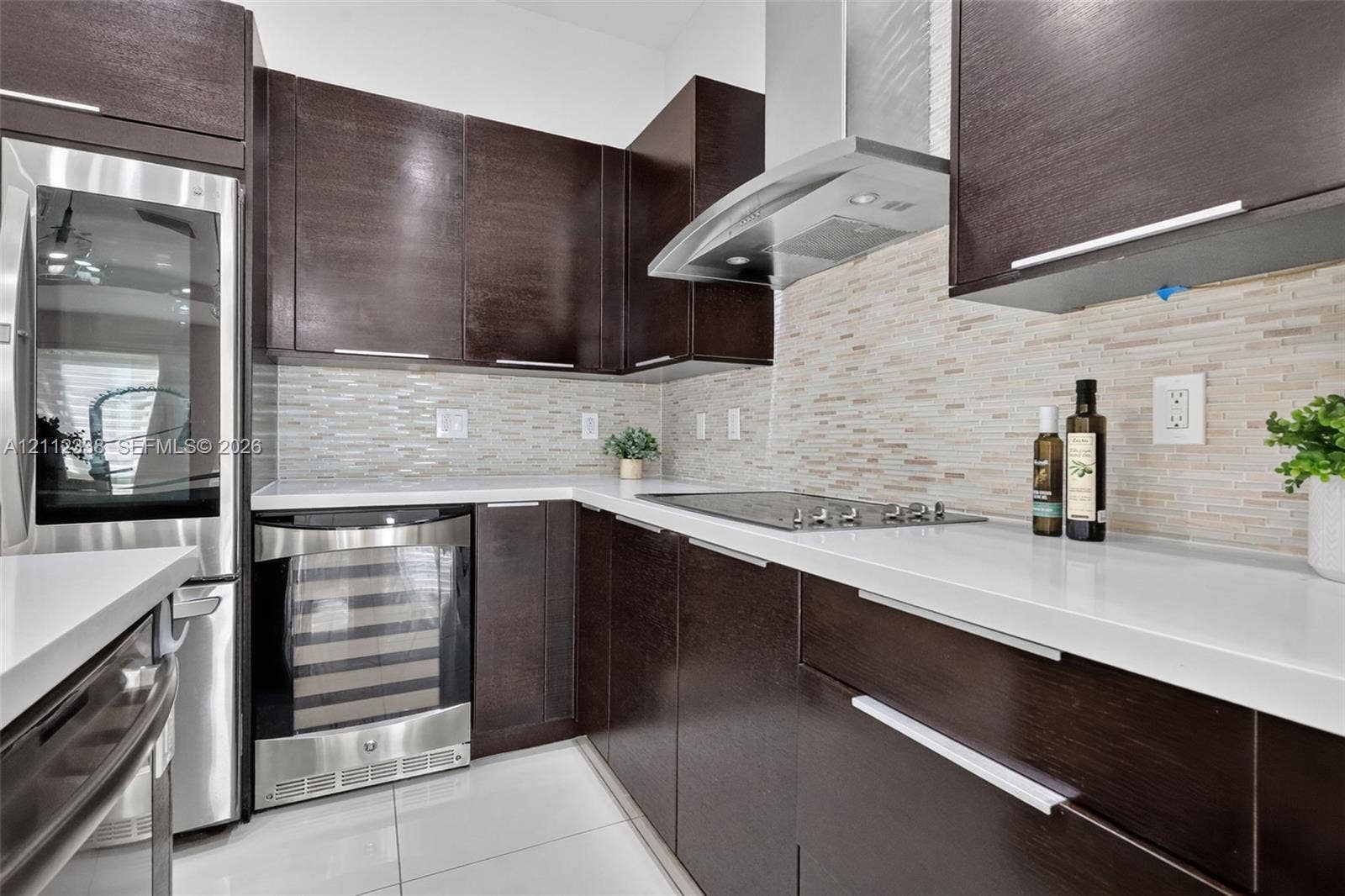 10305 NW 63rd Terrace, #102, Doral, FL 33178 Dark wood cabinetry with modern hardware, white quartz countertops, stainless steel appliances, tiled backsplash, and light-tone tile flooring