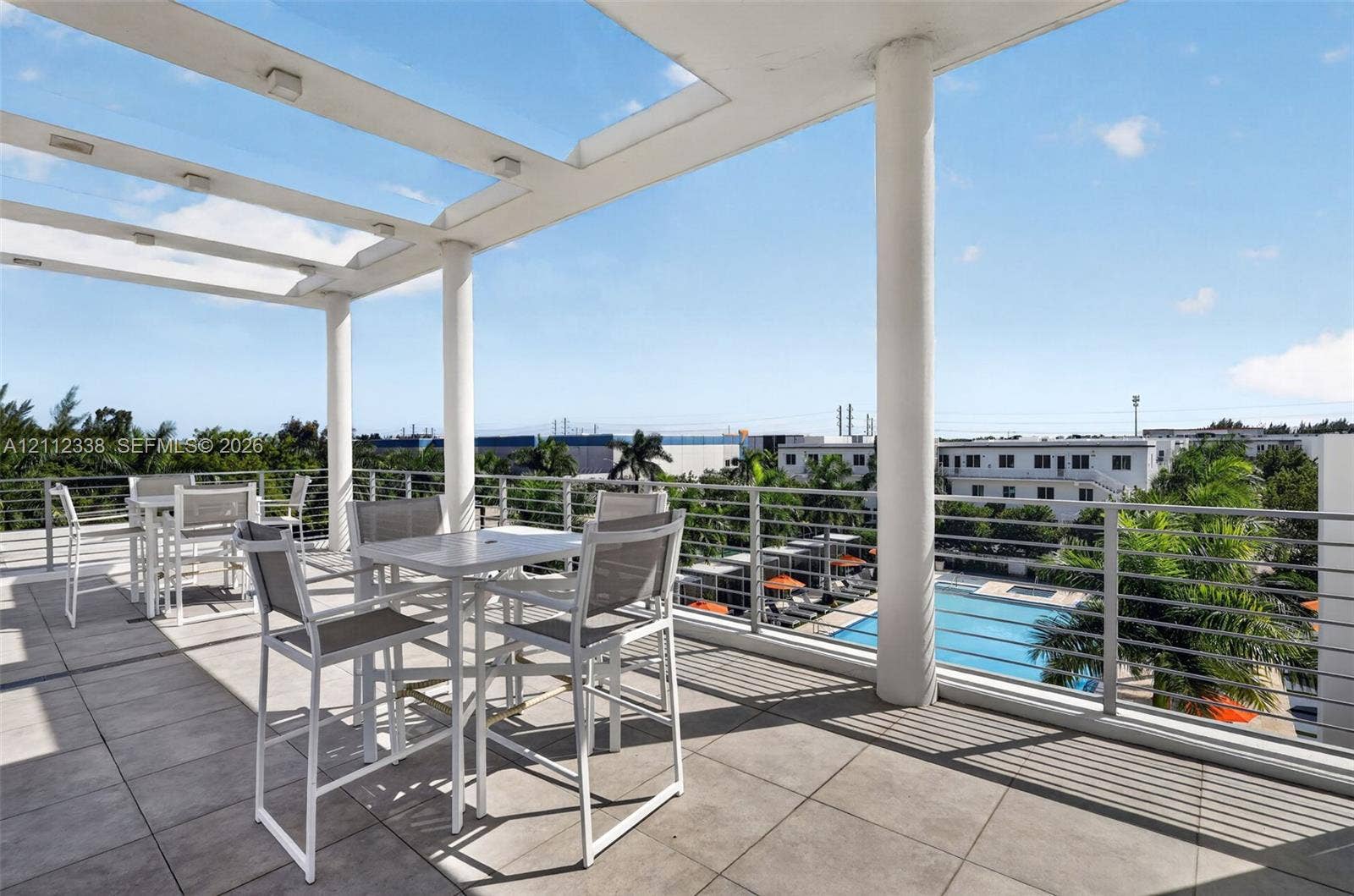 10305 NW 63rd Terrace, #102, Doral, FL 33178 Covered terrace featuring large-format tile flooring, a glass-paneled pergola with integrated lighting, and a stainless steel cable railing system