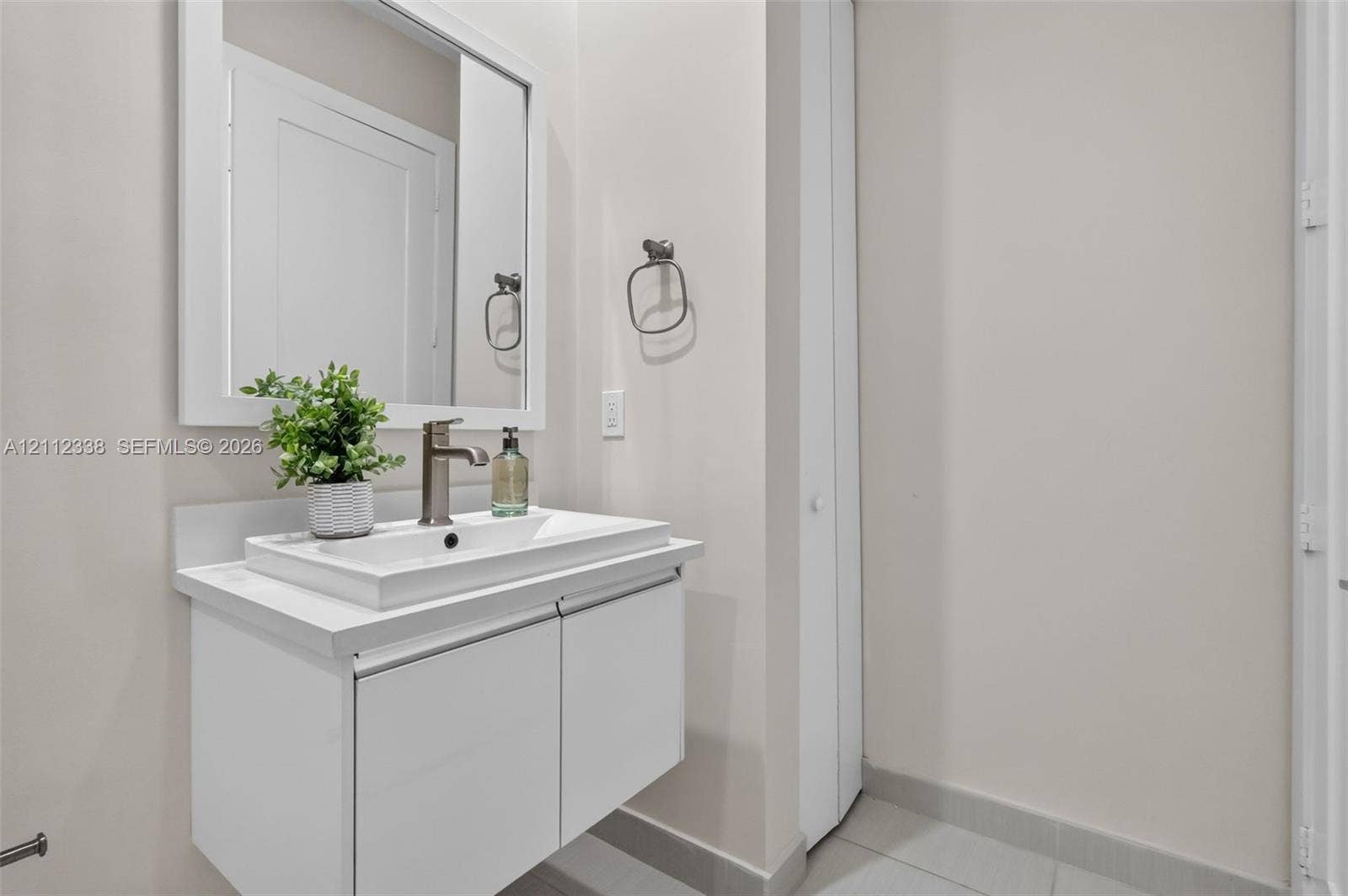 10305 NW 63rd Terrace, #102, Doral, FL 33178 Floating vanity featuring a white cabinetry finish, rectangular vessel sink, brushed metal faucet, and framed wall mirror