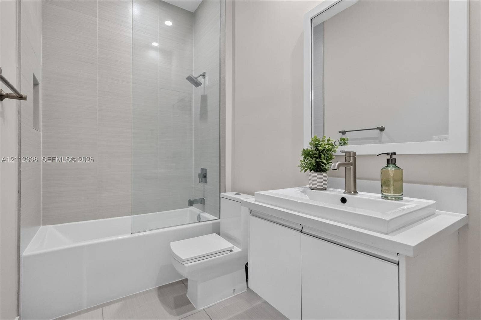 10305 NW 63rd Terrace, #102, Doral, FL 33178 Full bathroom featuring a white vanity with a rectangular vessel sink, solid surface countertop, glass shower panel, and light-toned wall tile