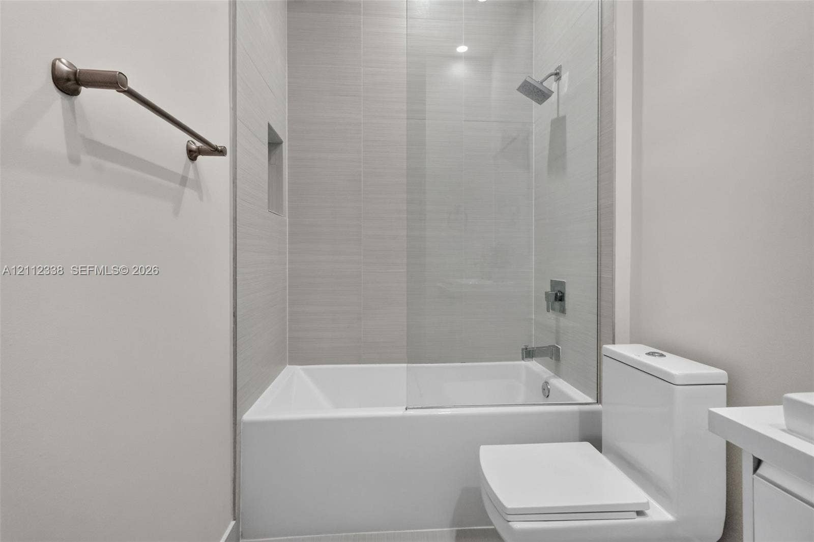 10305 NW 63rd Terrace, #102, Doral, FL 33178 Full-height tile surround with a recessed niche, frameless glass shower panel, and wall-mounted shower fixture