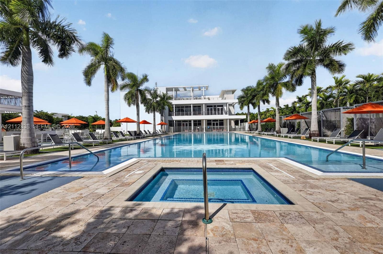 10305 NW 63rd Terrace, #102, Doral, FL 33178 Large swimming pool featuring a built-in spa, stone paver decking, and mature palm trees