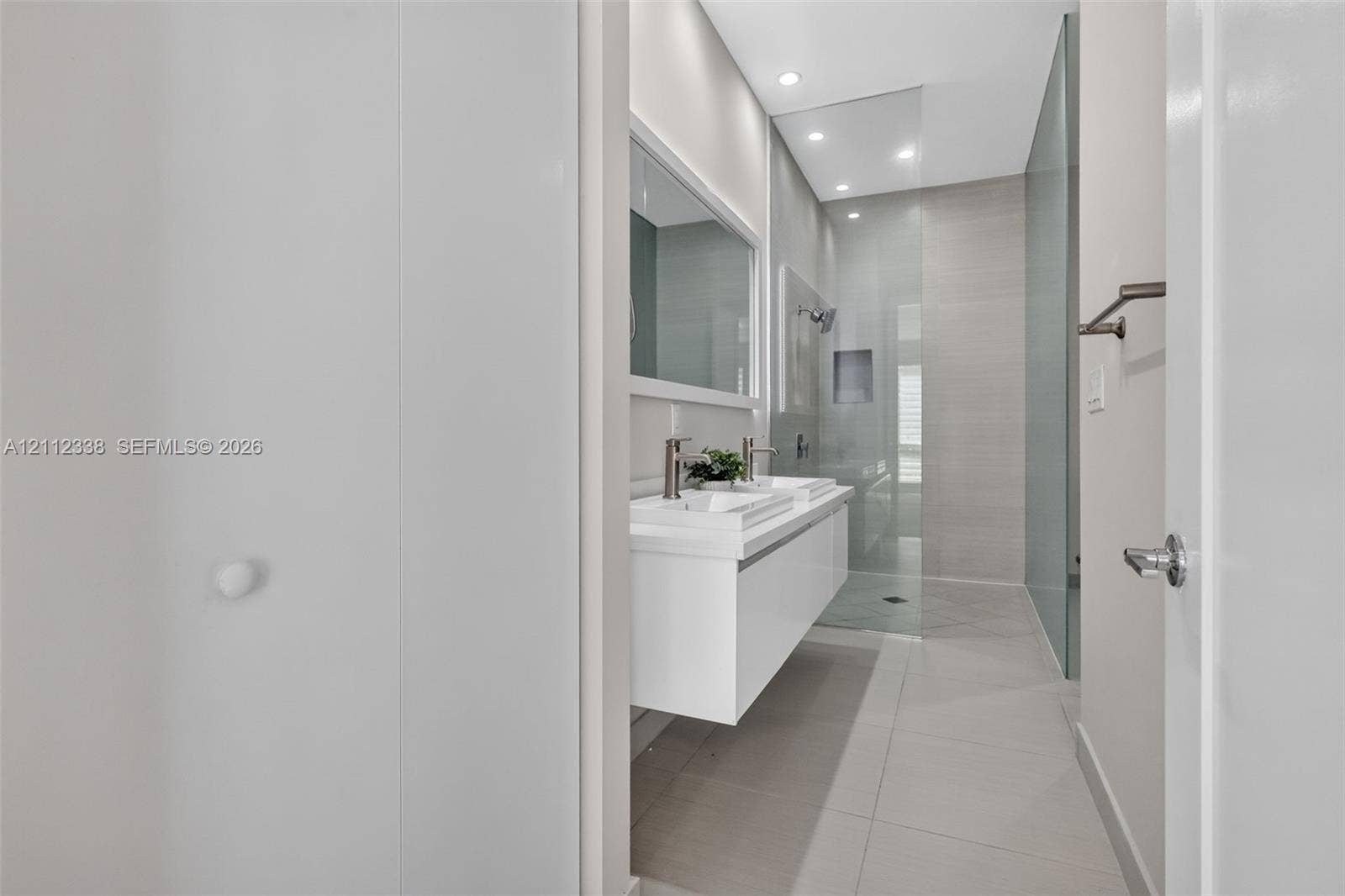10305 NW 63rd Terrace, #102, Doral, FL 33178 Modern floating dual vanity with integrated sinks, recessed lighting, large-format tile flooring, and a walk-in shower enclosed by a seamless glass panel