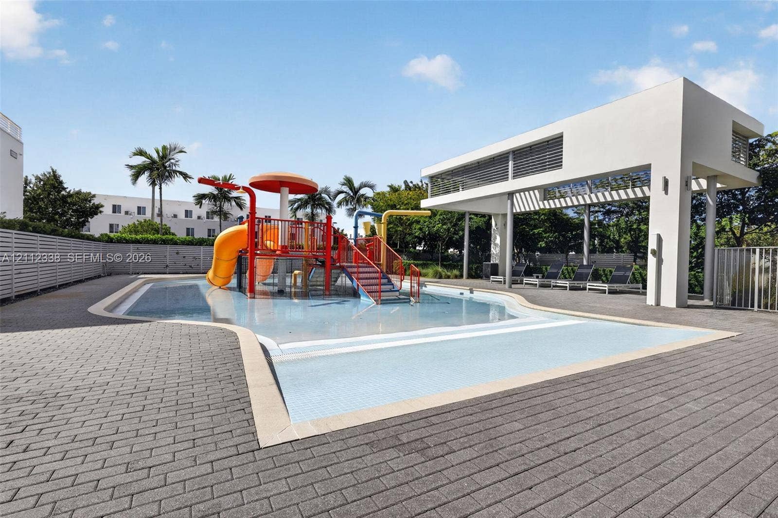 10305 NW 63rd Terrace, #102, Doral, FL 33178 Splash pad area featuring integrated water slides, a central mushroom-shaped fountain, a concrete paver deck, and a modern open-air covered pavilion
