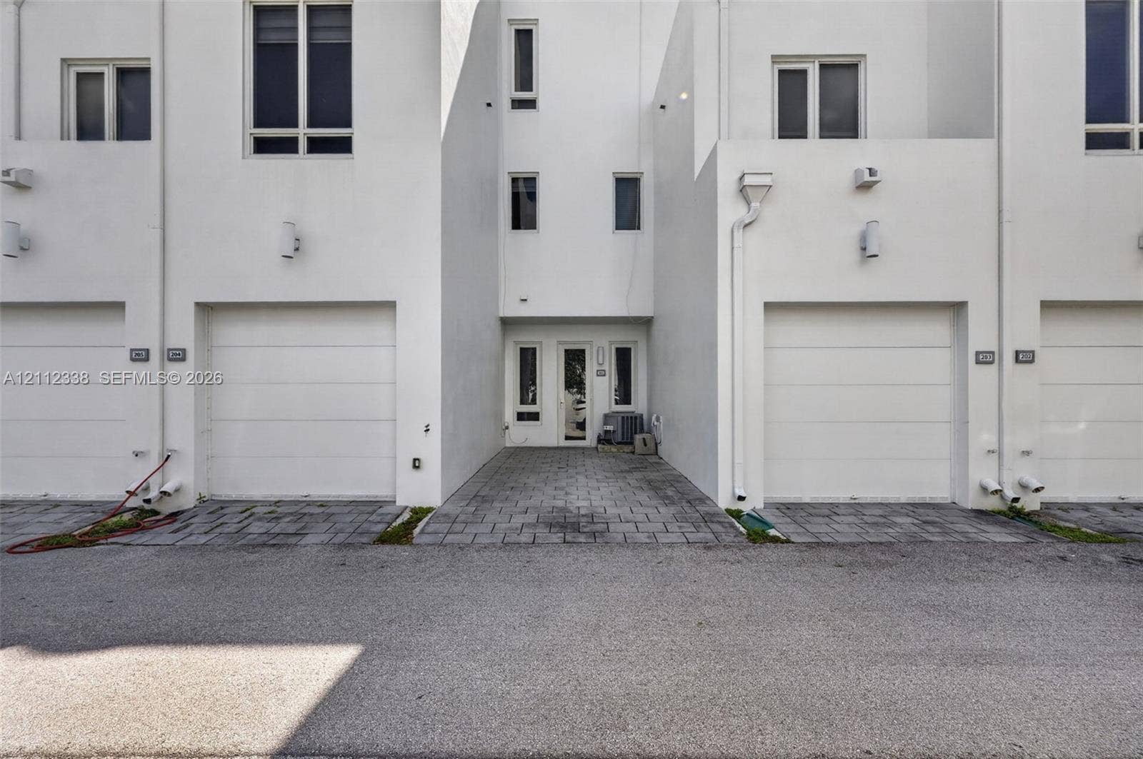 10305 NW 63rd Terrace, #102, Doral, FL 33178 Modern exterior featuring multi-level white stucco facade, paved driveway, and multiple integrated garage bays with overhead doors