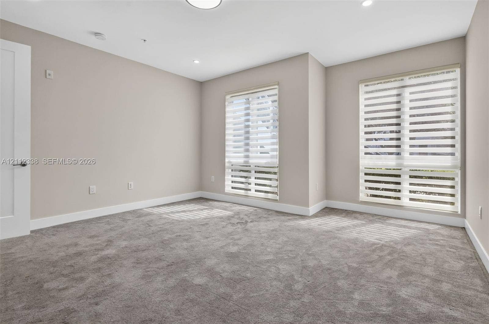 10305 NW 63rd Terrace, #102, Doral, FL 33178 Neutral-toned interior featuring wall-to-wall carpeting, recessed ceiling lighting, and two windows equipped with dual-layer zebra shades