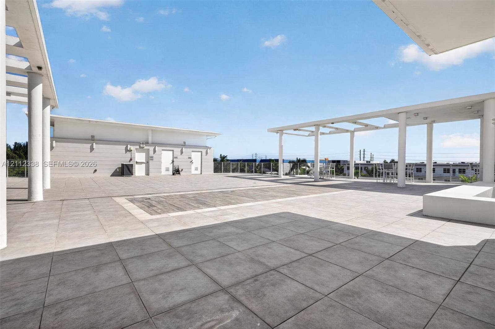 10305 NW 63rd Terrace, #102, Doral, FL 33178 Expansive rooftop terrace featuring large-format stone tile flooring, structural pergolas, and a perimeter railing