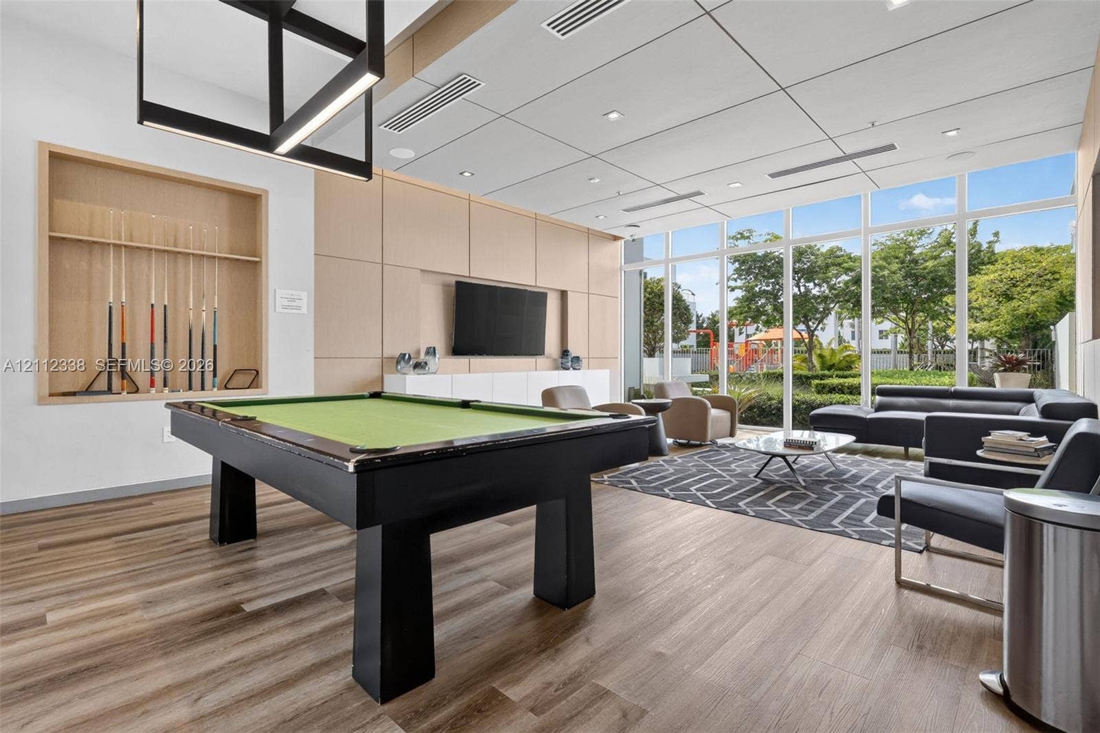 10305 NW 63rd Terrace, #102, Doral, FL 33178 Common area featuring floor-to-ceiling windows, wood-finish flooring, custom wood-panel wall treatments, integrated recessed lighting, and a modern geometric pendant fixture