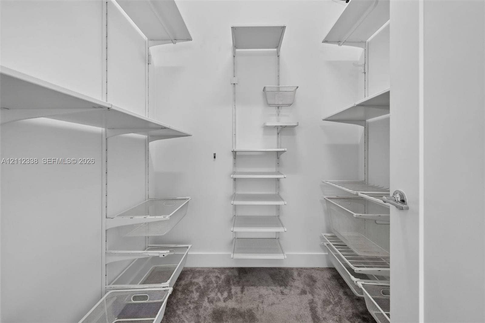 10305 NW 63rd Terrace, #102, Doral, FL 33178 Storage space featuring a customizable white wire shelving system with multiple tiered racks and integrated slide-out wire baskets, complete with wall-to-wall carpeting
