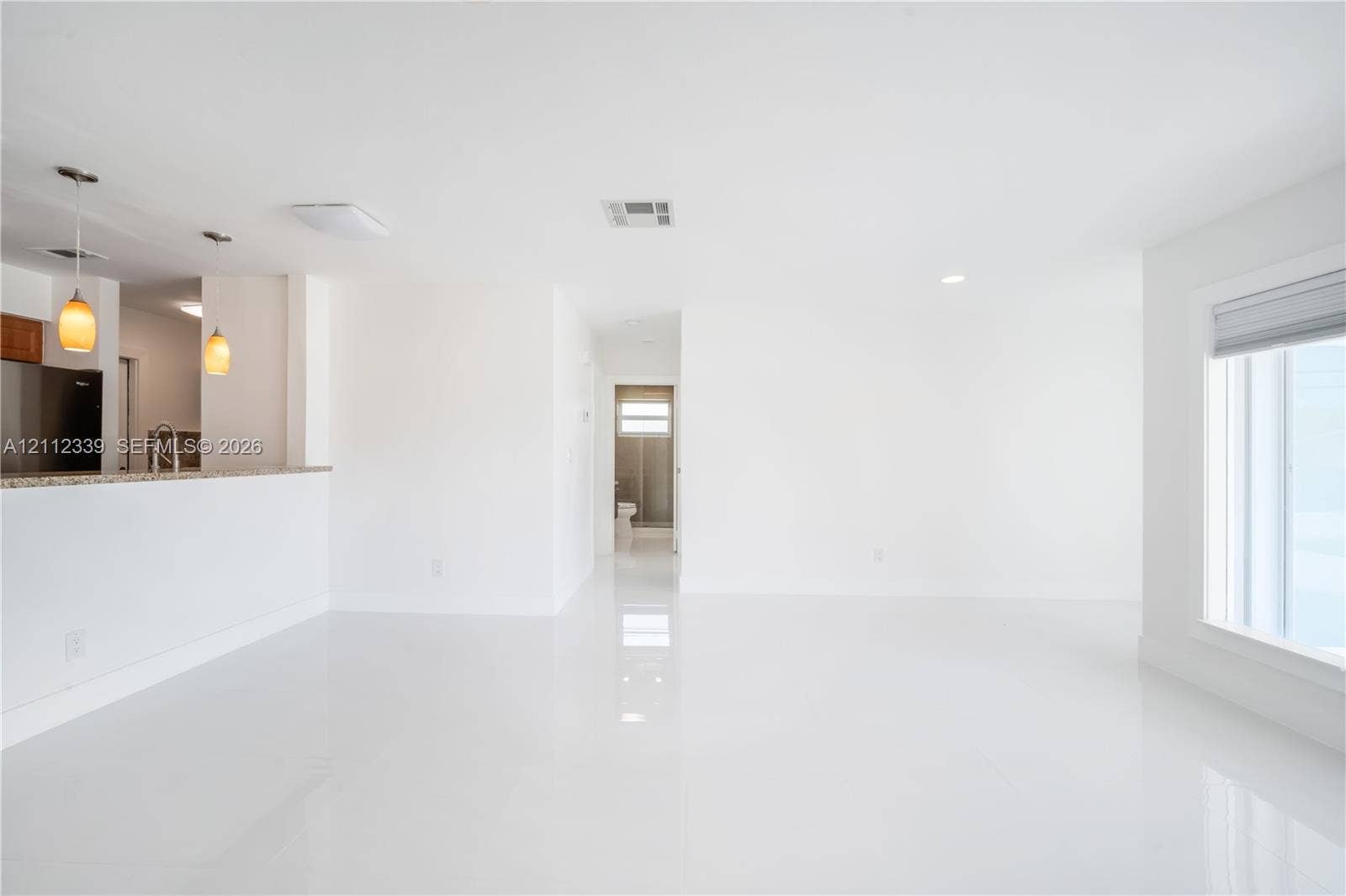 8901 SW 149th Terrace, #n/a, Palmetto Bay, Palmetto Bay, FL 33176 Open-concept interior featuring high-gloss tile flooring, recessed ceiling lighting, a kitchen peninsula with a stone-finish countertop, and two pendant light fixtures