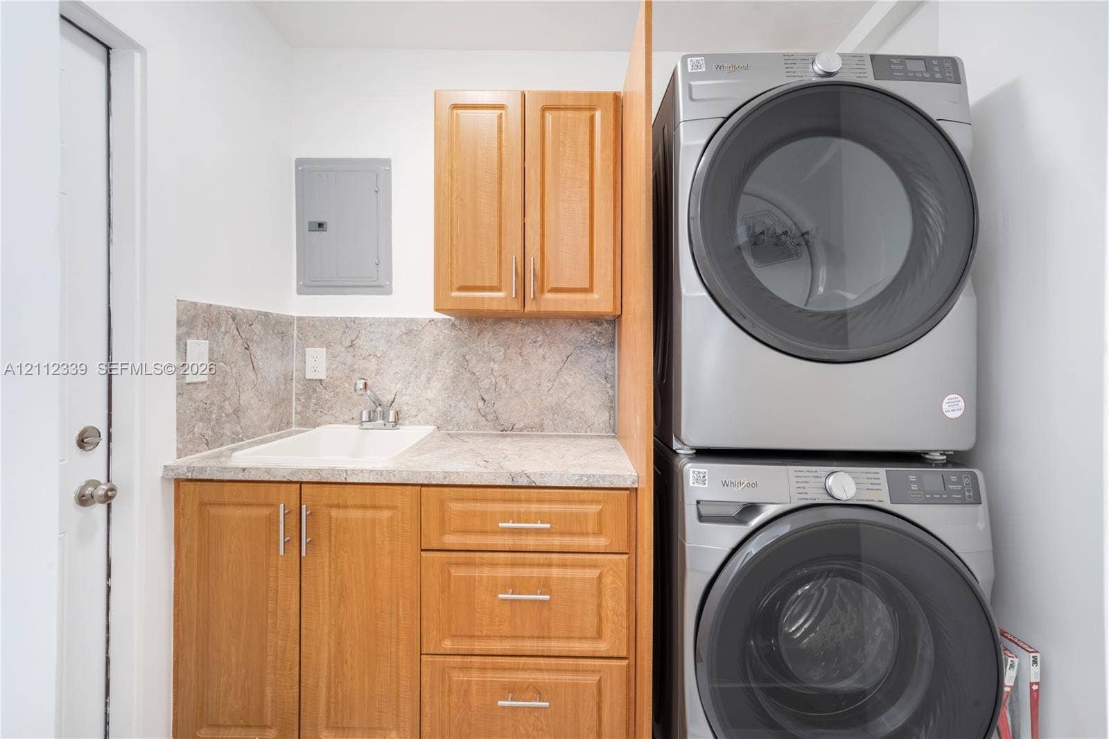 8901 SW 149th Terrace, #n/a, Palmetto Bay, Palmetto Bay, FL 33176 Laundry area featuring wooden cabinetry, a built-in utility sink, and stacked full sixed laundry appliances * Door on the left leads to the backyard *