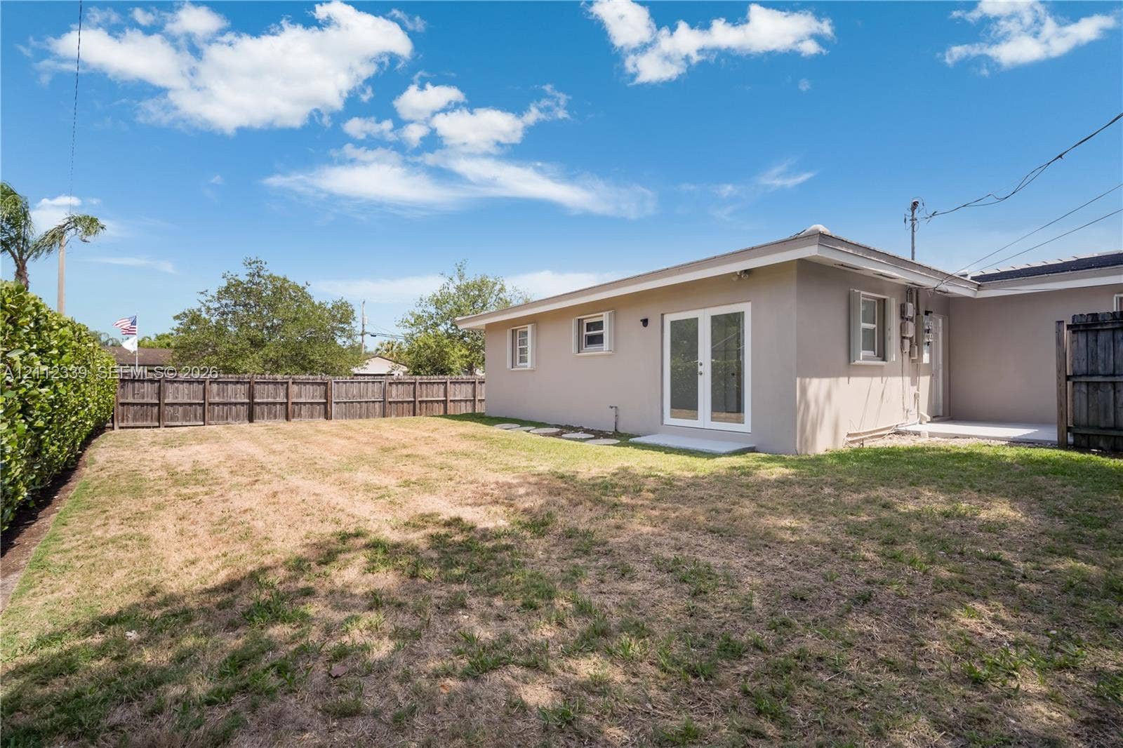 8901 SW 149th Terrace, #n/a, Palmetto Bay, Palmetto Bay, FL 33176 Private backyard featuring a privacy hedge, wood-panel fencing, and exterior French doors leading to one of the bedrooms *