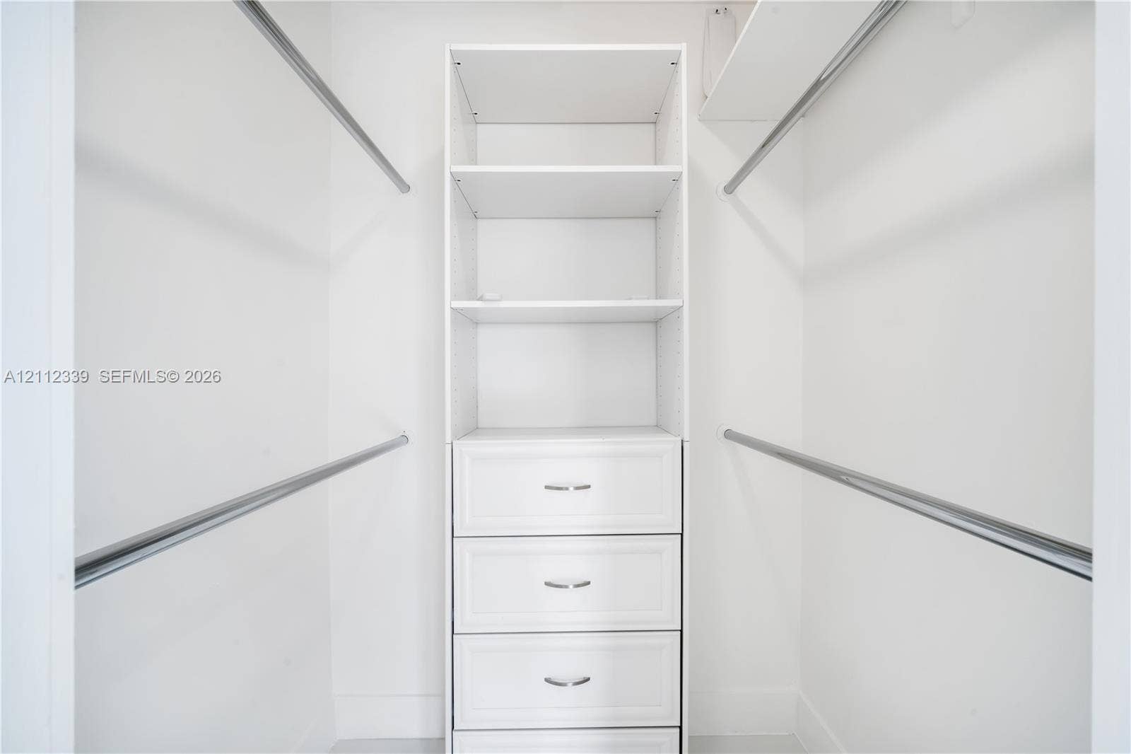 8901 SW 149th Terrace, #n/a, Palmetto Bay, Palmetto Bay, FL 33176 Custom walk-in closet featuring white built-in shelving, a four-drawer dresser unit with metallic pulls, and dual-level hanging rods