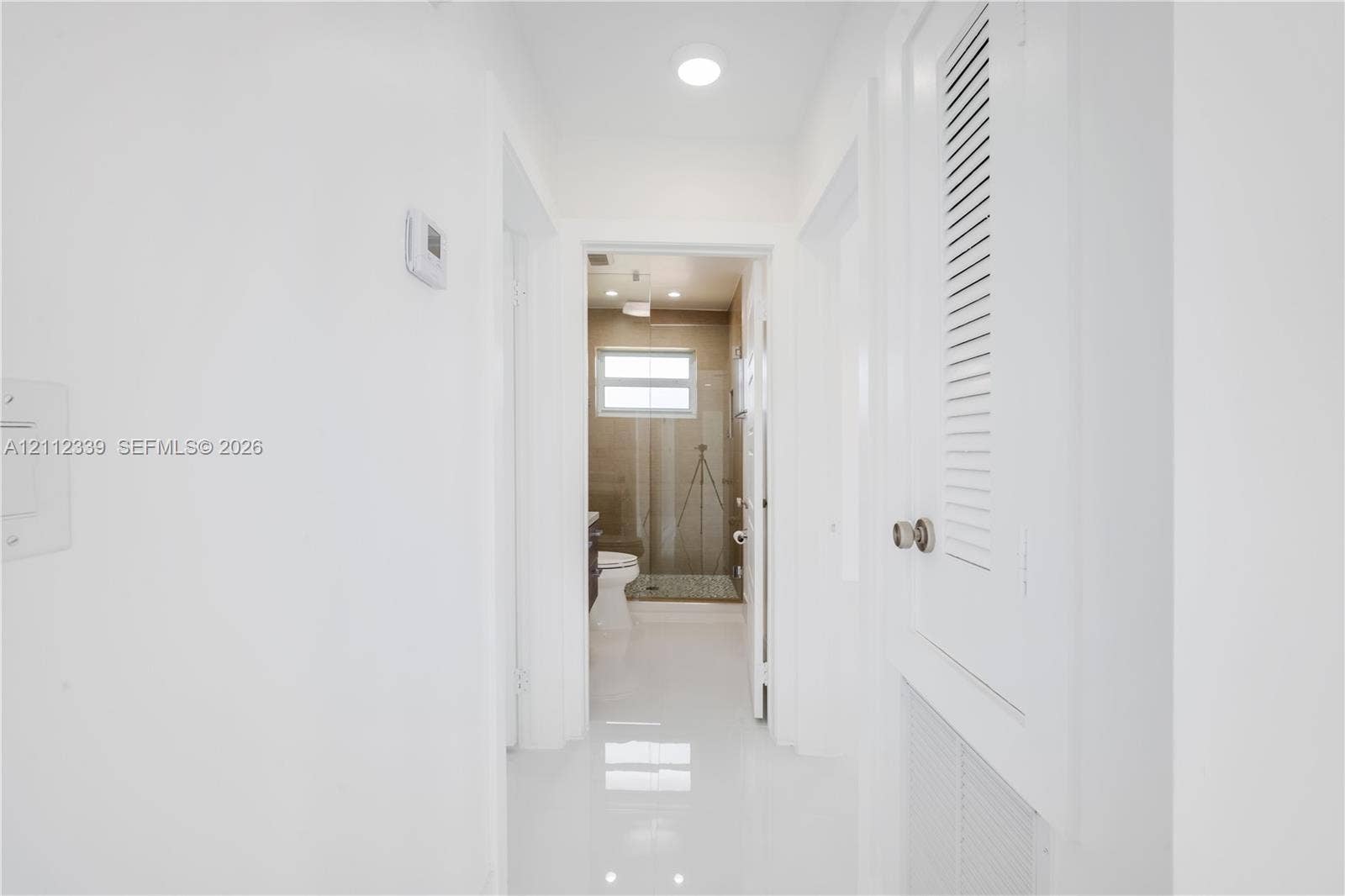 8901 SW 149th Terrace, #n/a, Palmetto Bay, Palmetto Bay, FL 33176 Hallway featuring crisp white walls, polished tile flooring, and built-in closet cabinetry with louvered doors