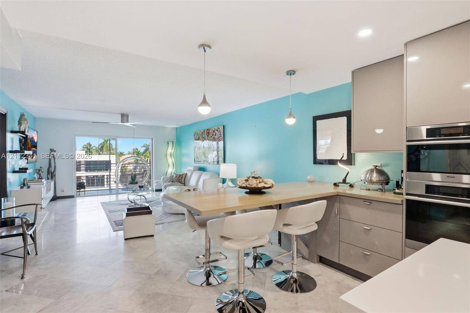 1617 SE 15th Street, #401, Fort Lauderdale, FL 33316 Open-concept kitchen featuring high-gloss cabinetry, stone-finish flooring, built-in stainless steel double wall ovens, and a peninsula with integrated breakfast bar seating
