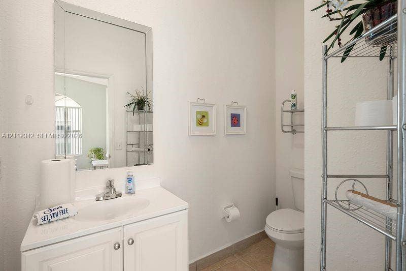 Vanity featuring a white cabinet base, integrated sink, and polished chrome faucet, paired with a beveled-edge wall mirror and neutral tile flooring