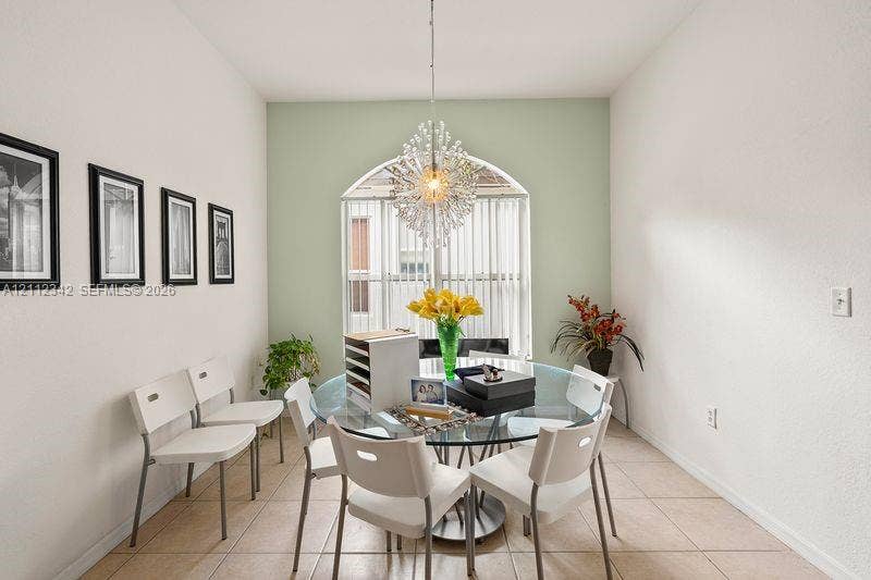 Arched window with vertical blinds, tile flooring, and a crystal-style chandelier fixture