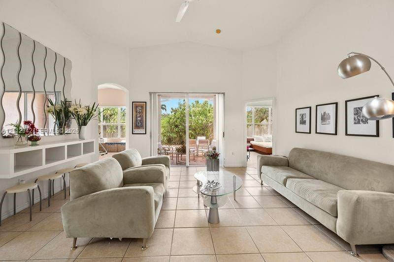 Living area featuring vaulted ceilings, oversized tile flooring, built-in wall cabinetry, and glass sliding doors