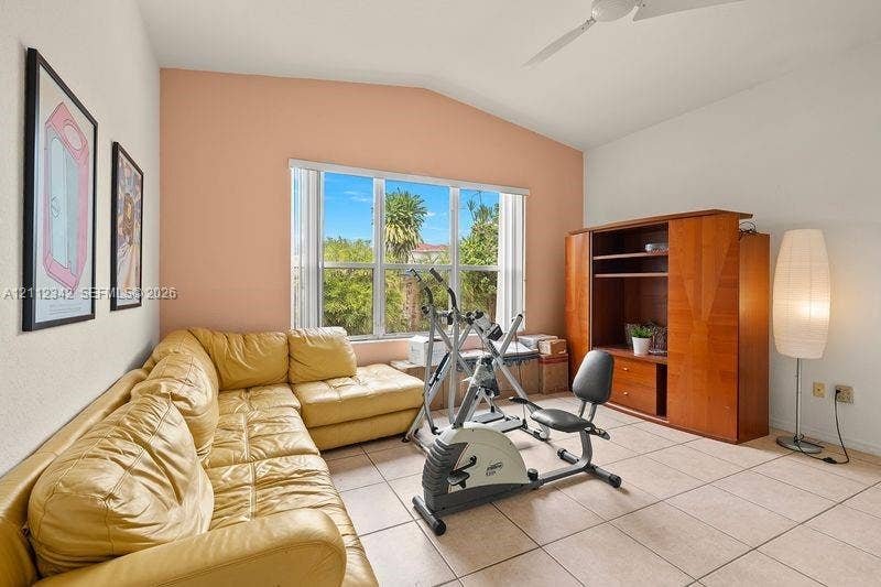 Vaulted ceiling, ceramic tile flooring, built-in wooden cabinetry, and large multi-pane windows