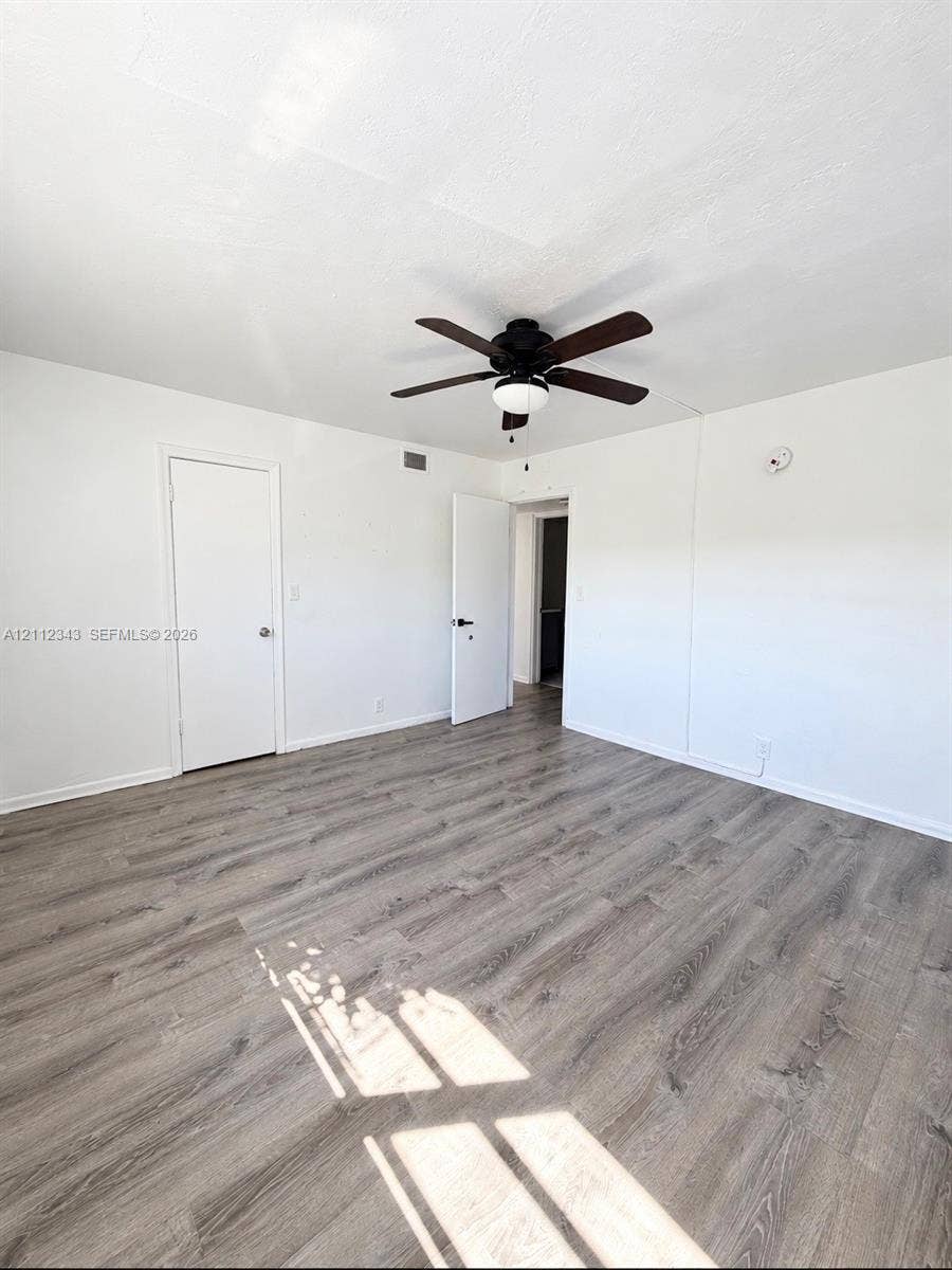 1477 SW 24th Court, #5, Fort Lauderdale, Fort Lauderdale, FL 33315 Interior room featuring wood-finish flooring, a multi-blade ceiling fan with integrated lighting, and two doors