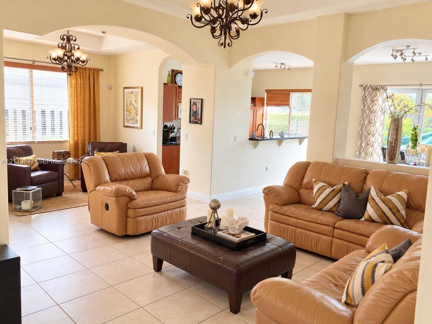 8766 NW 139th Terrace, #139, Miami Lakes, Miami Lakes, FL 33018 Open-concept interior featuring arched wall openings, large-format tile flooring, tiered ceiling detail, and wrought-iron style chandelier fixtures