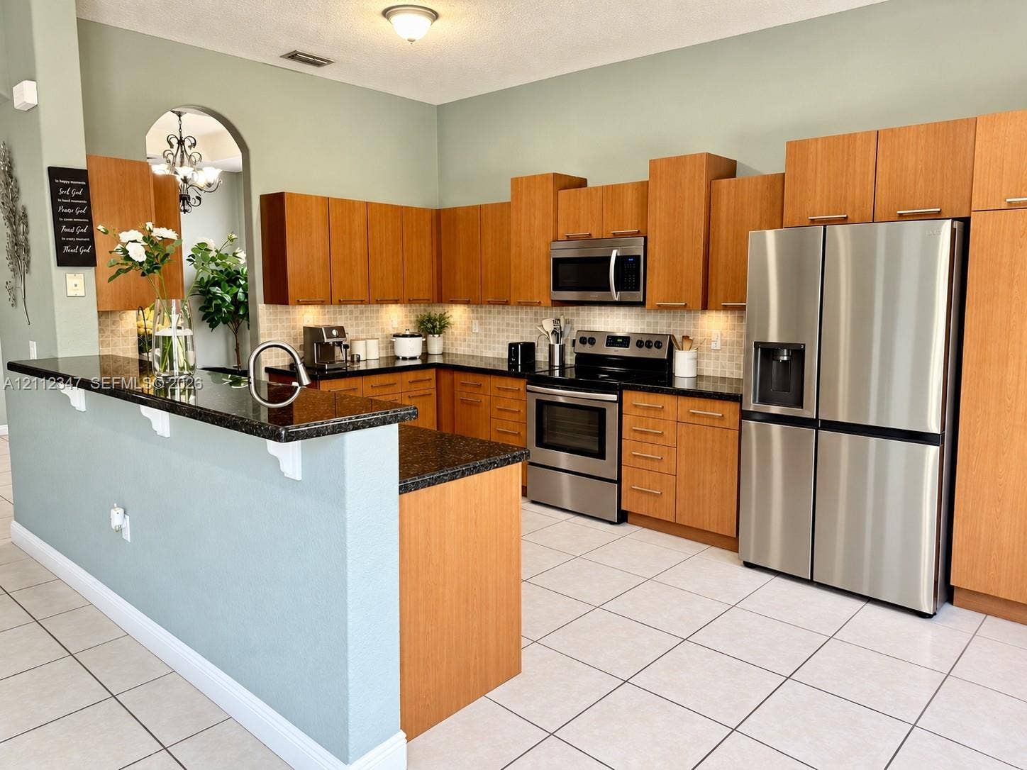 8766 NW 139th Terrace, #139, Miami Lakes, Miami Lakes, FL 33018 Kitchen featuring wood cabinetry, stone countertops, stainless steel appliances, tiled backsplash, and a breakfast bar