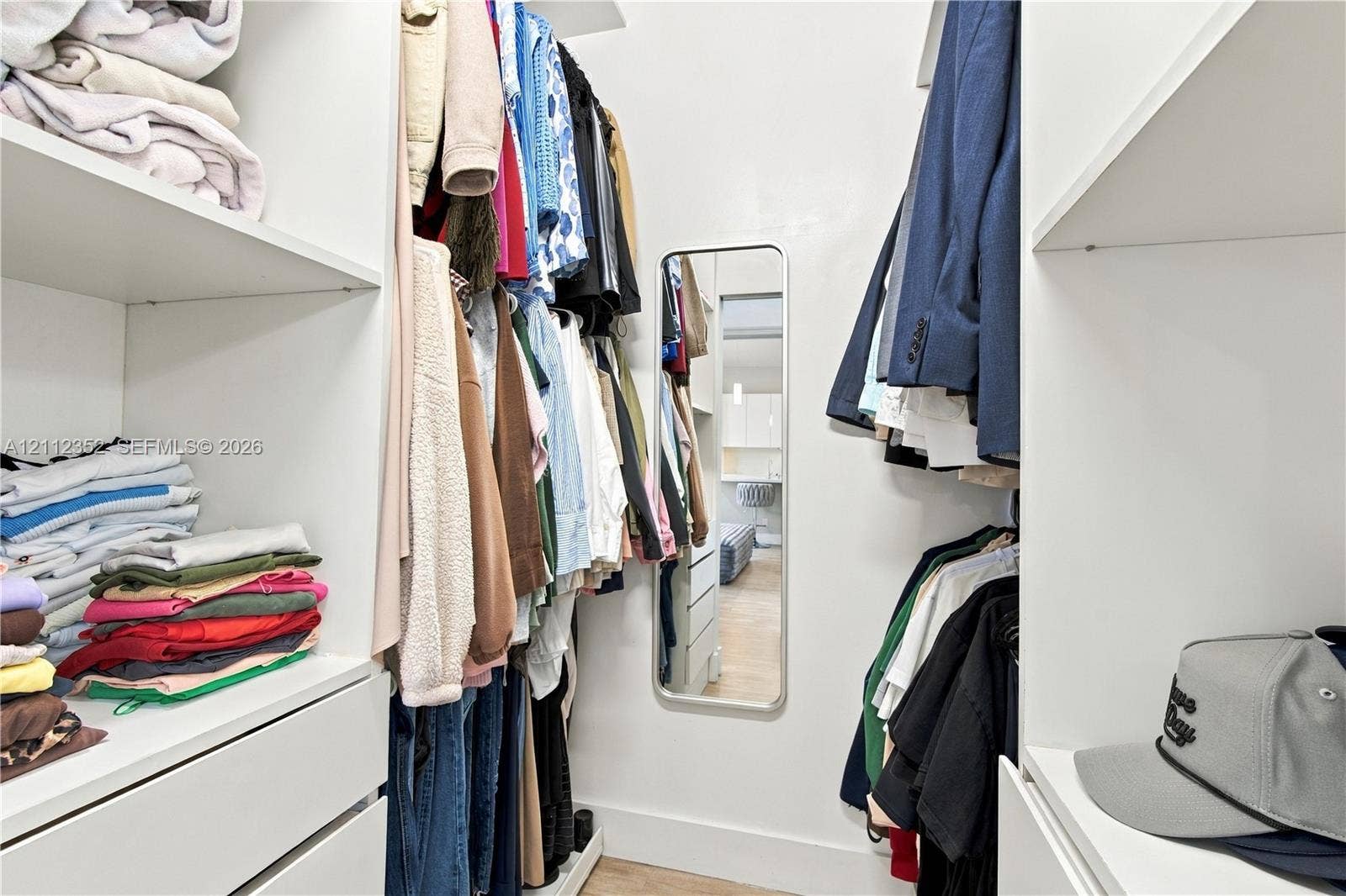 2880 NW 75th Avenue, Margate, FL 33063 Walk-in closet featuring white custom built-in shelving, hanging rods, integrated drawer storage, and a wall-mounted rectangular mirror