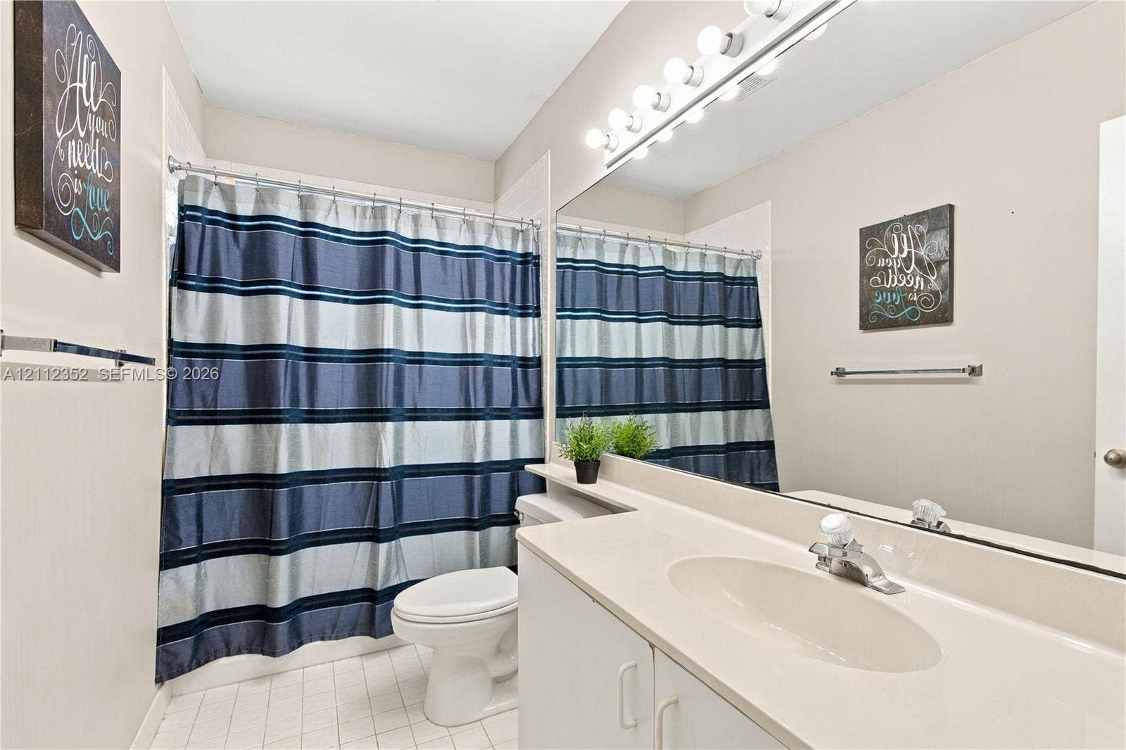 2880 NW 75th Avenue, Margate, FL 33063 Bathroom featuring a vanity with integrated sink, expansive wall-to-wall mirror, multi-bulb vanity lighting, and tile flooring