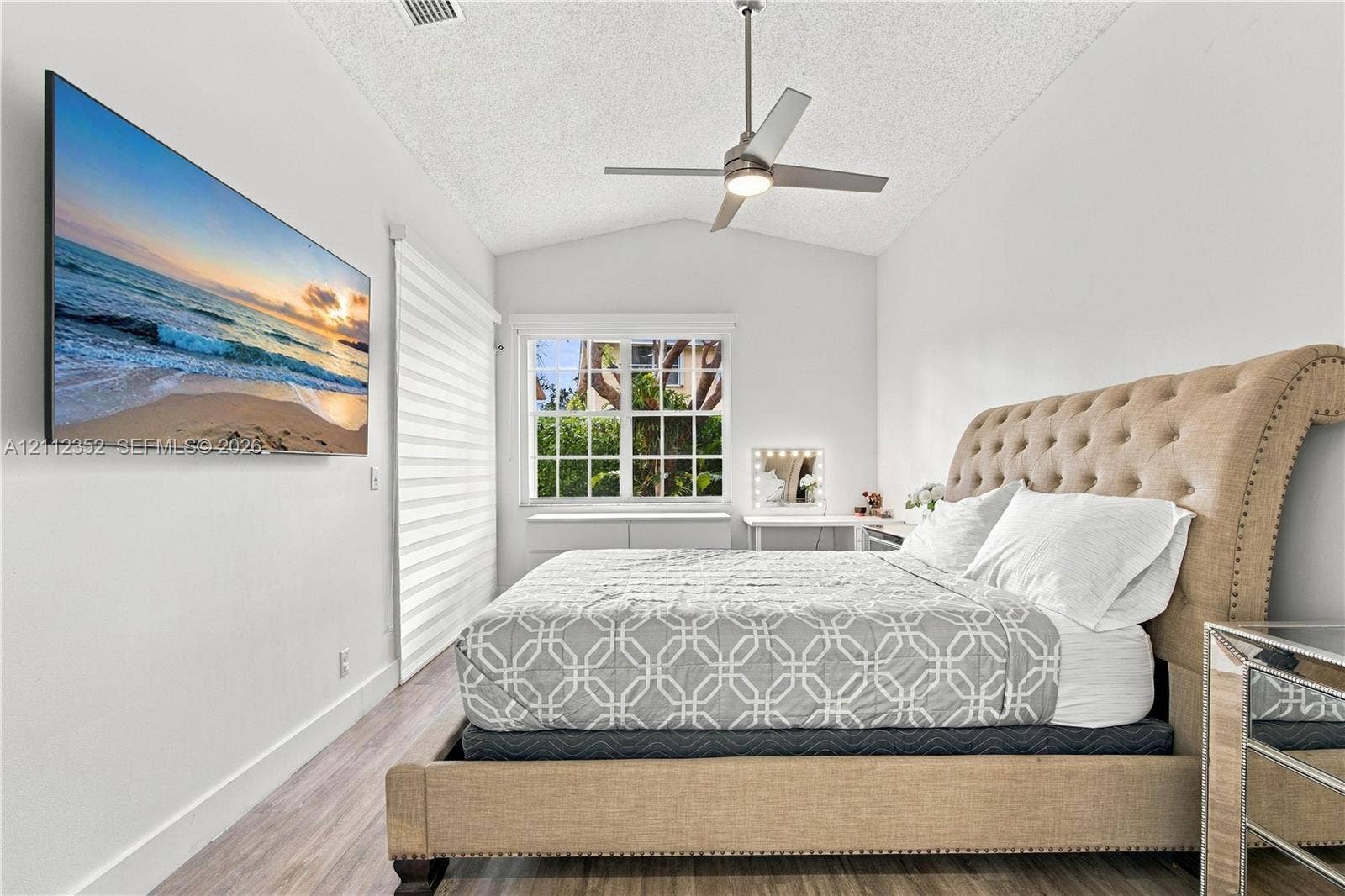 2880 NW 75th Avenue, Margate, FL 33063 Vaulted ceiling featuring a central brushed-metal ceiling fan, wood-finish flooring, and a multi-pane window