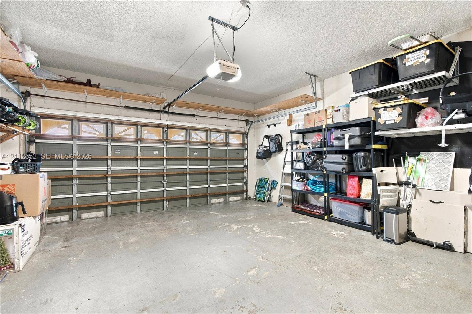 2880 NW 75th Avenue, Margate, FL 33063 Multi-car garage featuring a sectional door with windows, integrated ceiling-mounted lighting, and extensive wall-mounted wood shelving