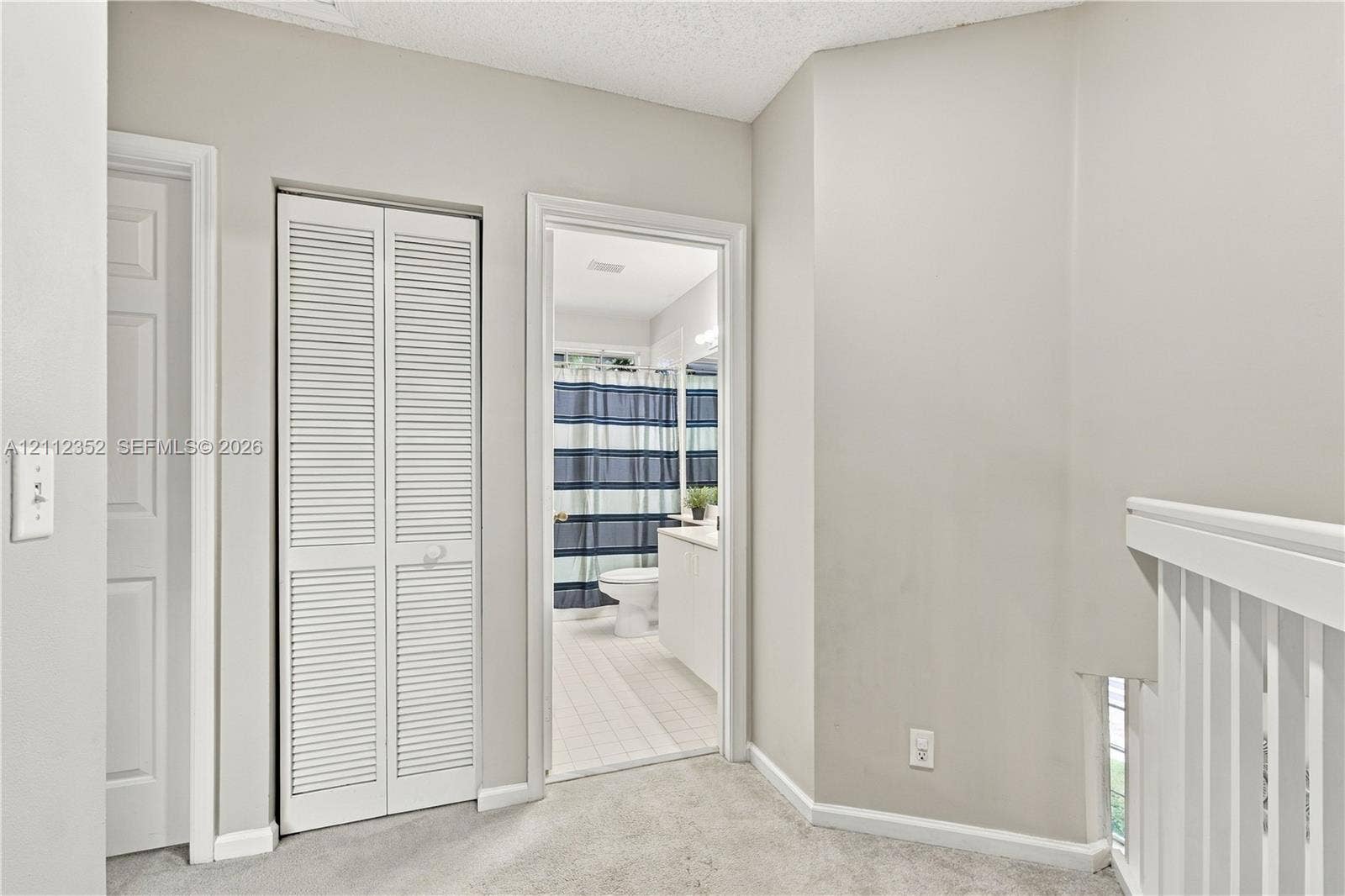 2880 NW 75th Avenue, Margate, FL 33063 Neutral-toned interior featuring louvered bifold closet doors, white painted millwork, and carpeted flooring