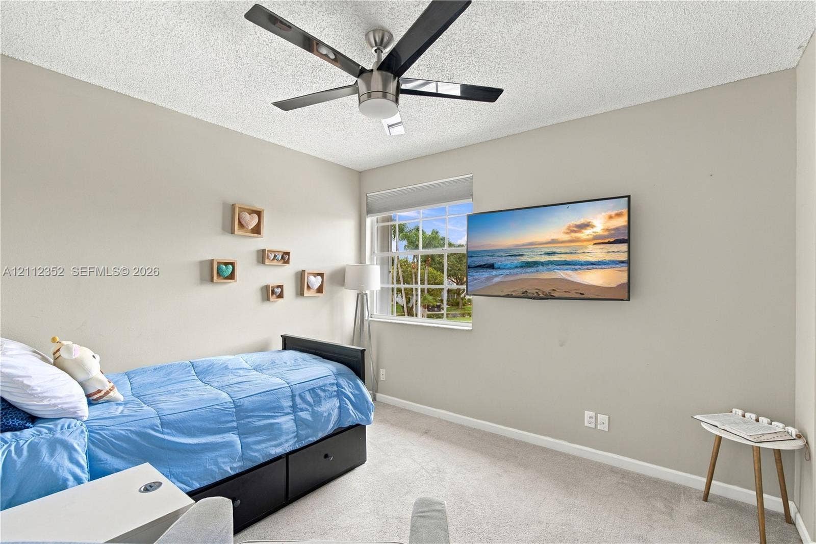 2880 NW 75th Avenue, Margate, FL 33063 Room featuring a brushed-nickel ceiling fan with dark-toned blades, neutral wall paint, carpeting, and a grid-pattern window
