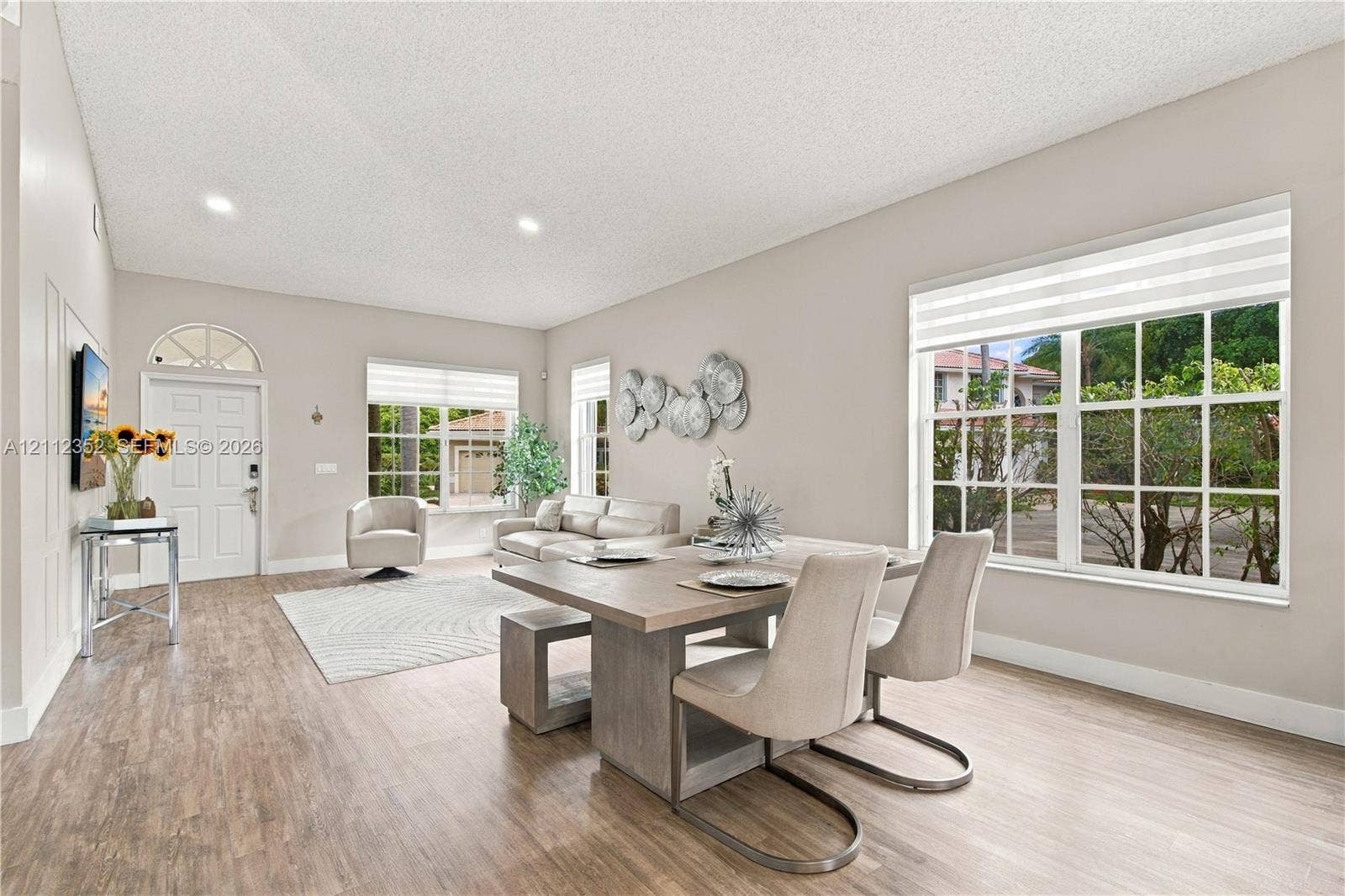 2880 NW 75th Avenue, Margate, FL 33063 Open-concept living space featuring wood-finish flooring, recessed lighting, multiple oversized windows, and a front entry door with a transom window