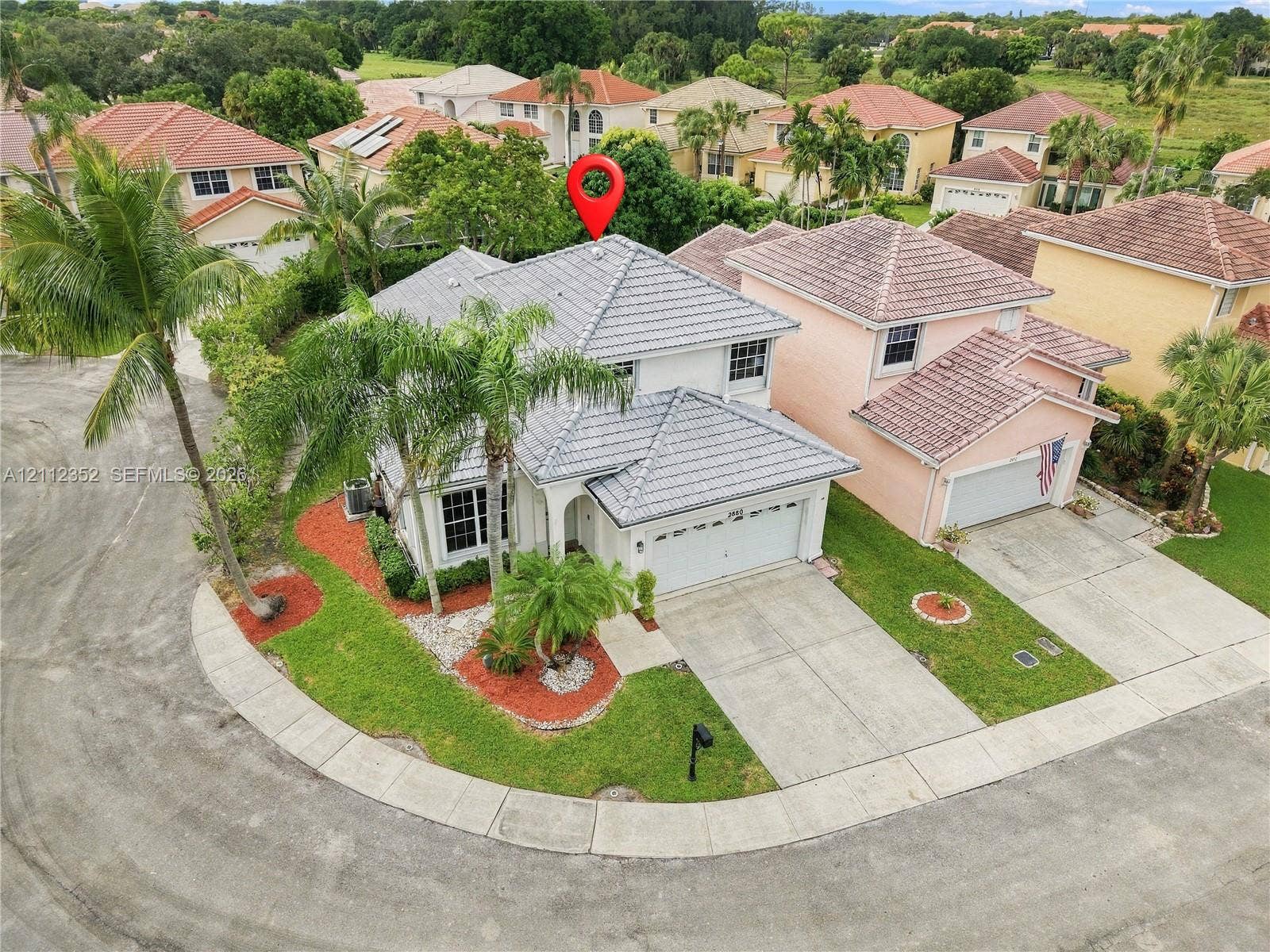 2880 NW 75th Avenue, Margate, FL 33063 Two-story residence featuring a concrete tile roof, attached two-car garage, concrete driveway, and established palm tree landscaping