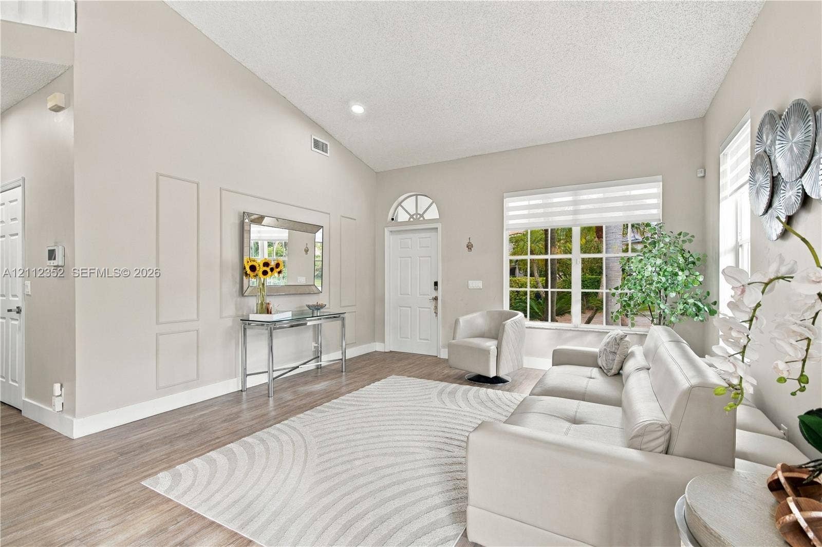 2880 NW 75th Avenue, Margate, FL 33063 Living room featuring vaulted ceilings, wood-finish flooring, wall molding detail, and a front entry door with a transom window