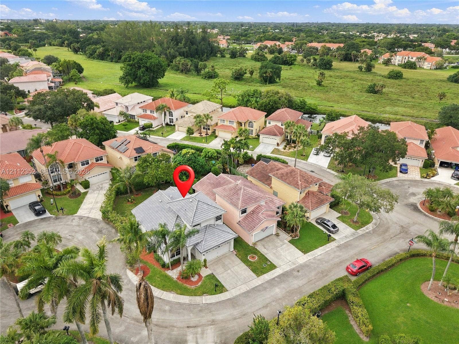 2880 NW 75th Avenue, Margate, FL 33063 Aerial perspective featuring a tile roof, multi-level architectural design, attached garage, and paved driveway situated within a suburban landscape