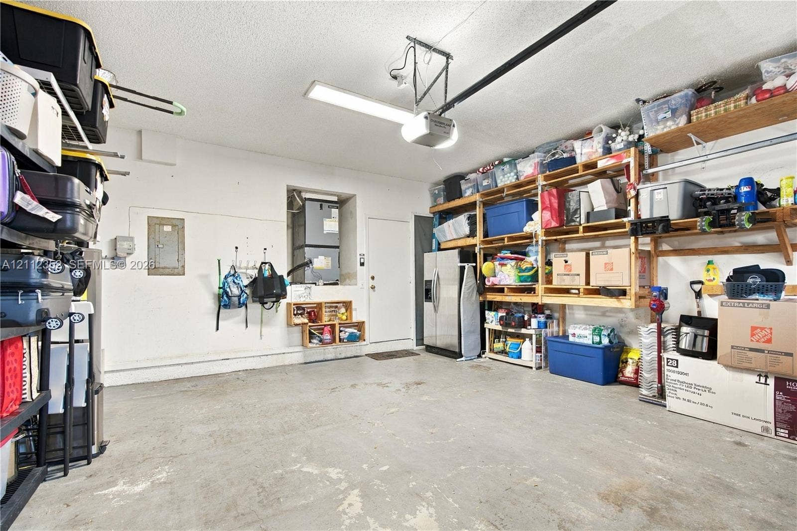 2880 NW 75th Avenue, Margate, FL 33063 Garage featuring concrete flooring, built-in wall shelving, an overhead automatic door opener, and a dedicated utility closet