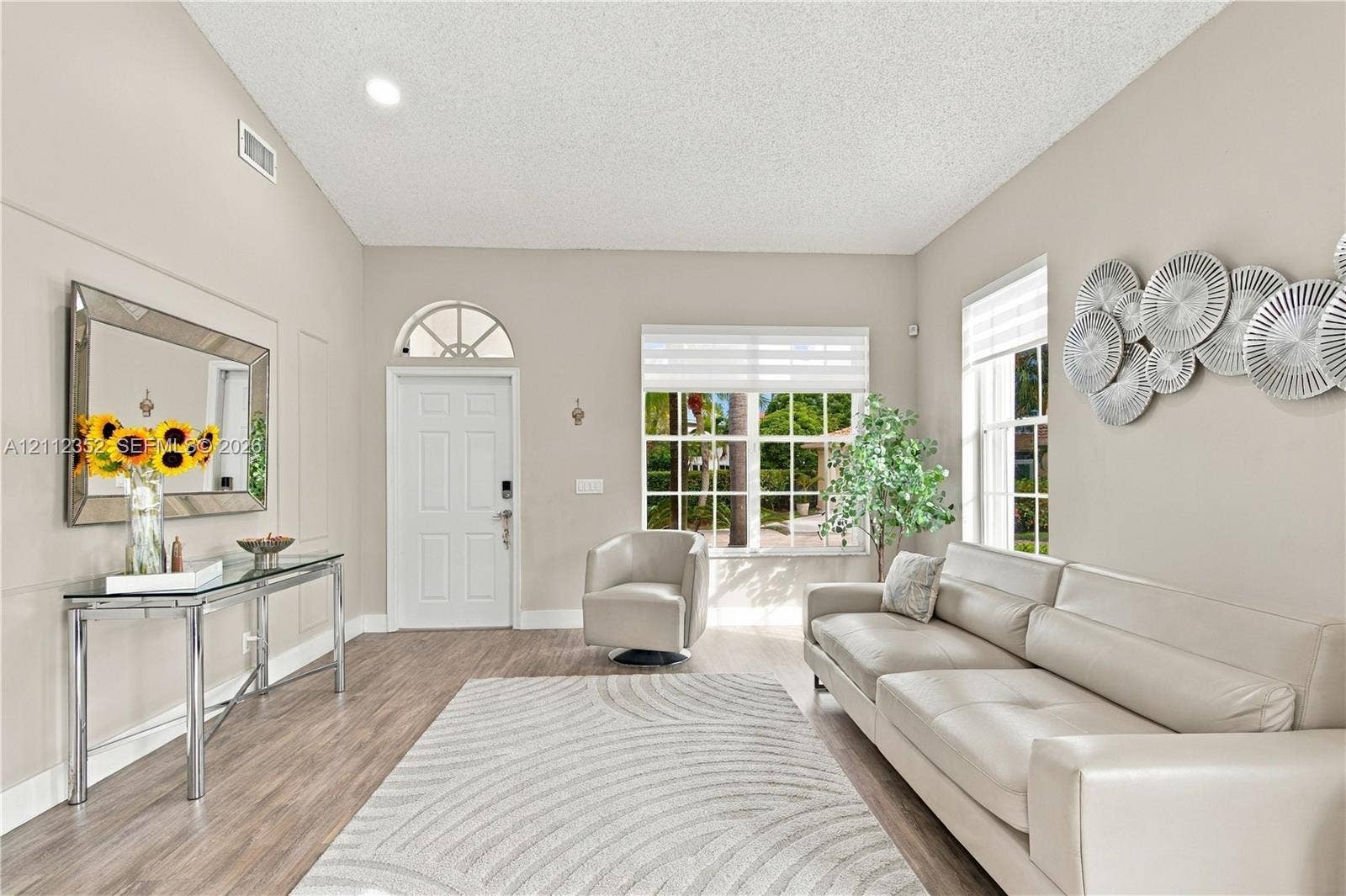 2880 NW 75th Avenue, Margate, FL 33063 High-ceilinged room featuring wood-finish flooring, a multi-pane entry door with a semi-circular transom window, and oversized windows with integrated blinds