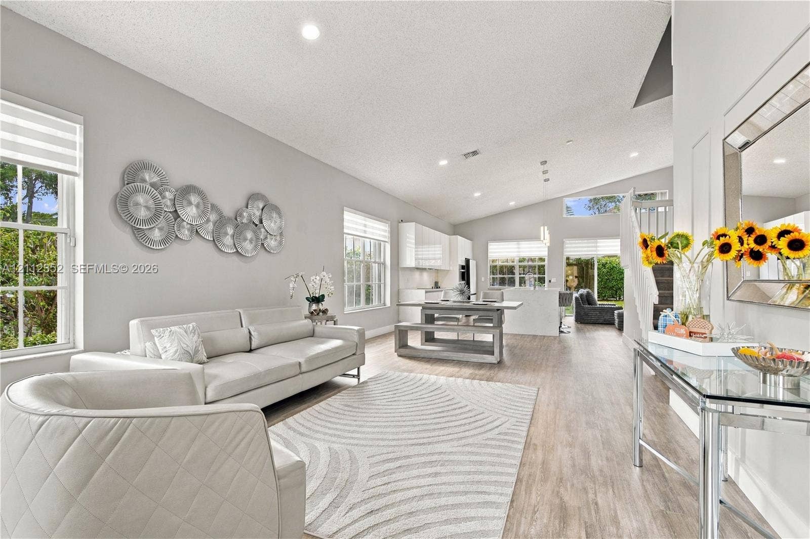 2880 NW 75th Avenue, Margate, FL 33063 Open-concept interior featuring vaulted ceilings, wood-finish flooring, recessed lighting, and multiple windows with integrated blinds