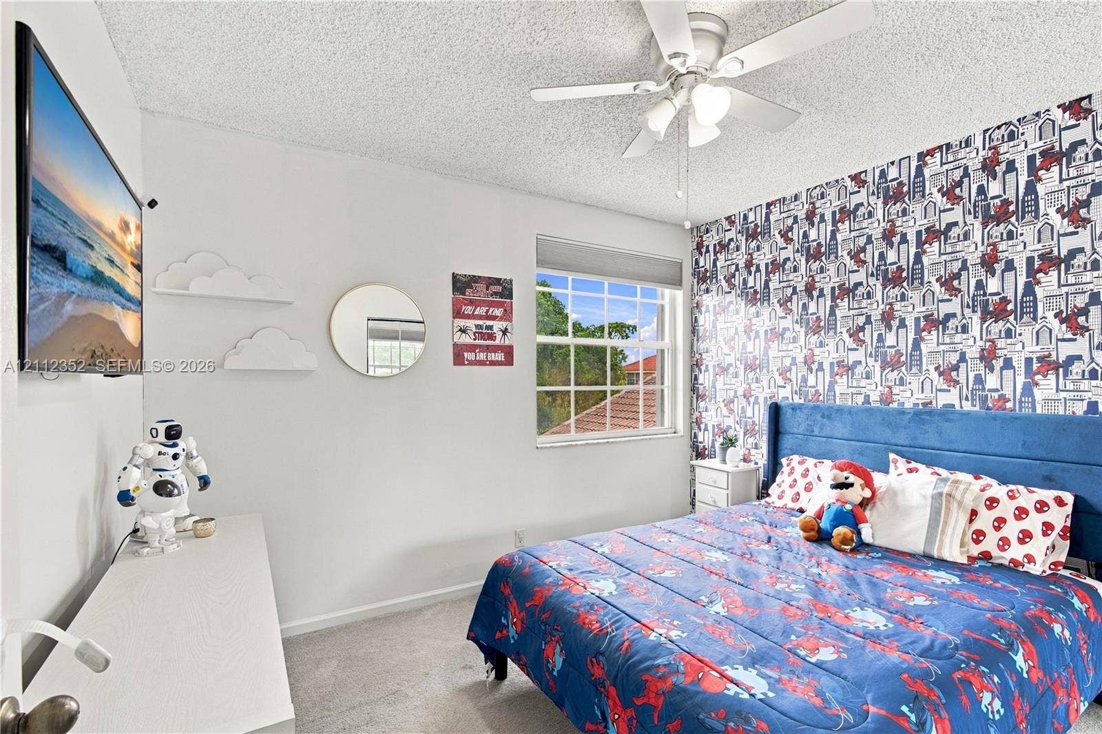 2880 NW 75th Avenue, Margate, FL 33063 Bedroom featuring a ceiling fan with integrated lighting, a grid-patterned window, and patterned accent wall covering