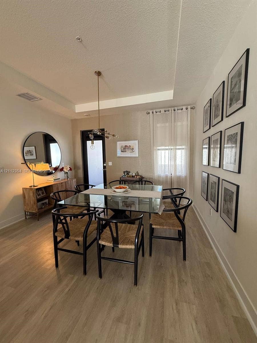 Tray ceiling, wood-finish flooring, and multi-light hanging pendant fixture