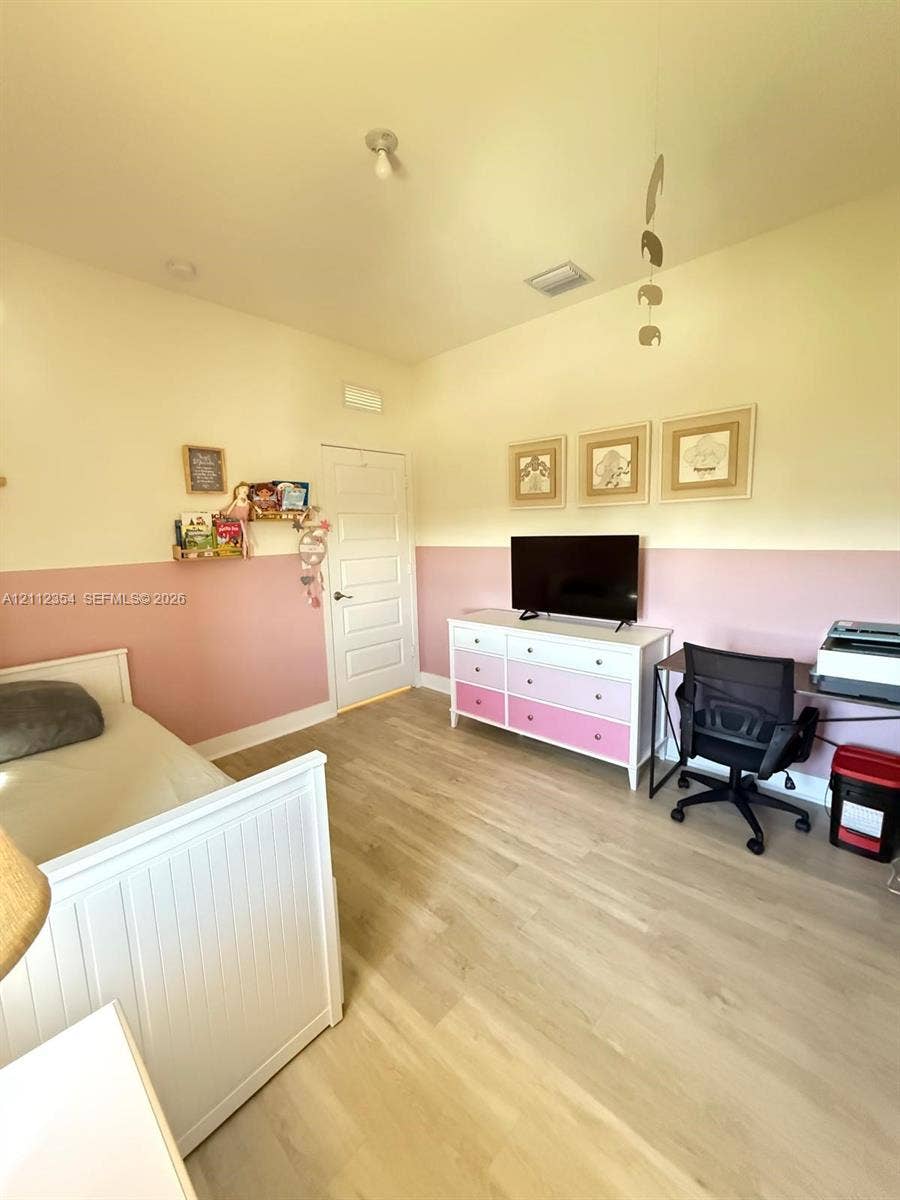 Room featuring two-toned painted walls, wood-finish flooring, and a single-panel interior door