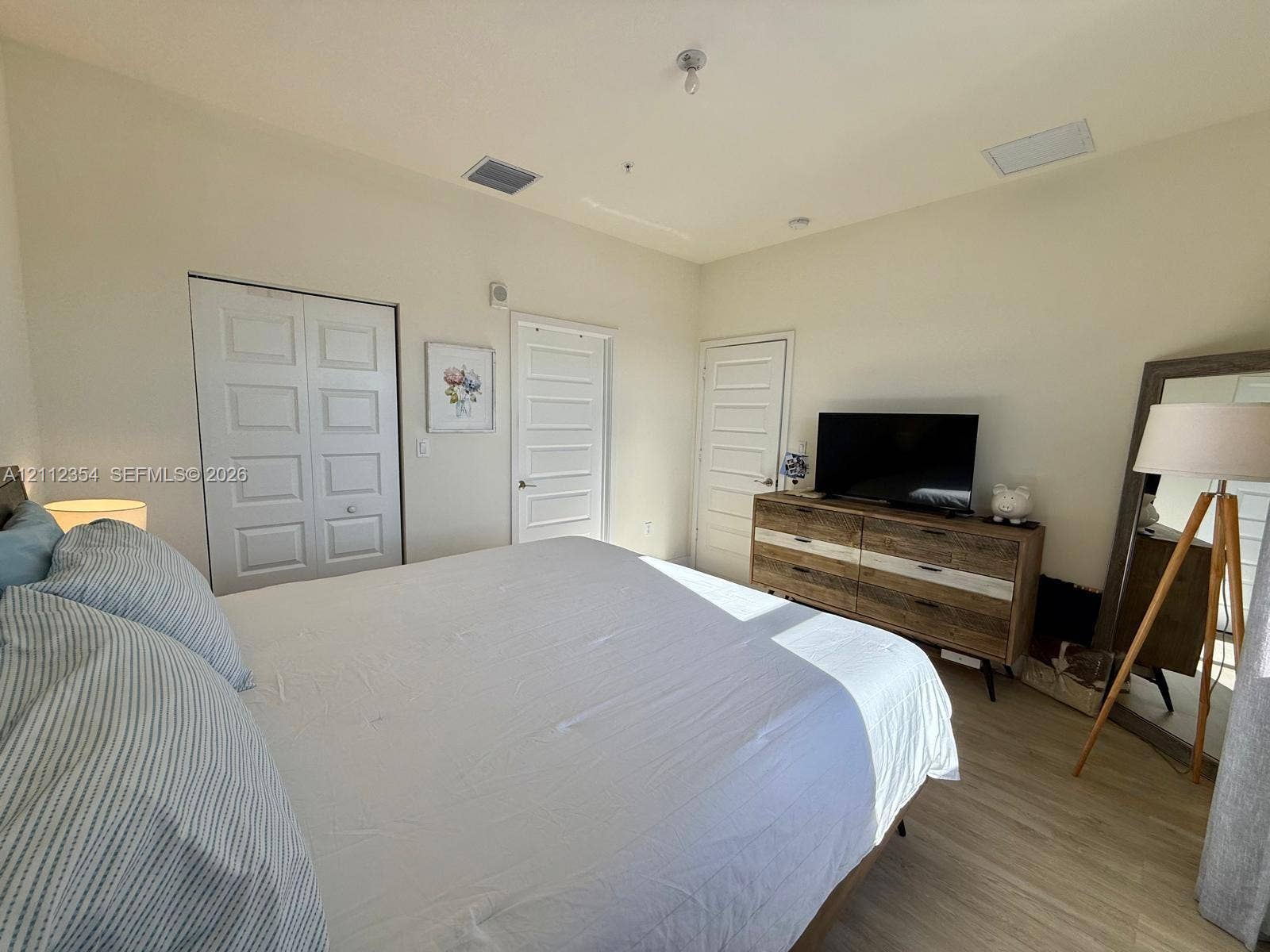 Bedroom featuring wood-finish flooring, high ceilings, neutral wall color, and multiple five-panel interior doors