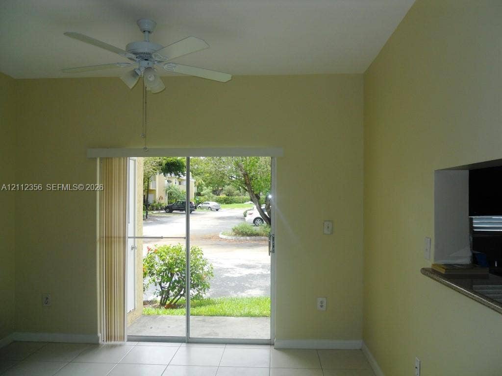 Neutral wall finishes, ceramic tile flooring, ceiling fan with integrated lighting, and a sliding glass door with vertical blinds