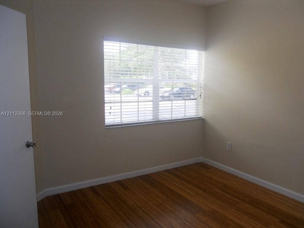 Room featuring wood-finish flooring, neutral wall paint, and a window with horizontal blinds