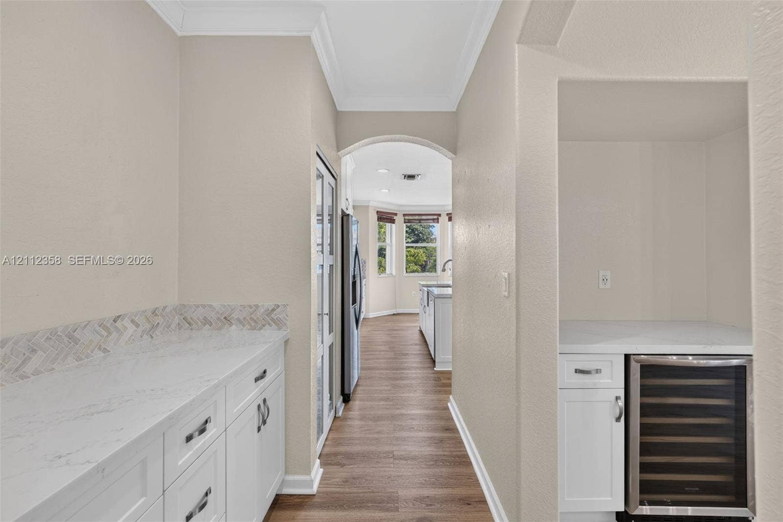 1611 SE 16th Street, Homestead, FL 33035 Butler pantry featuring white cabinetry, light-toned stone-finish countertops, a herringbone-patterned tile backsplash, and a built-in stainless steel beverage refrigerator