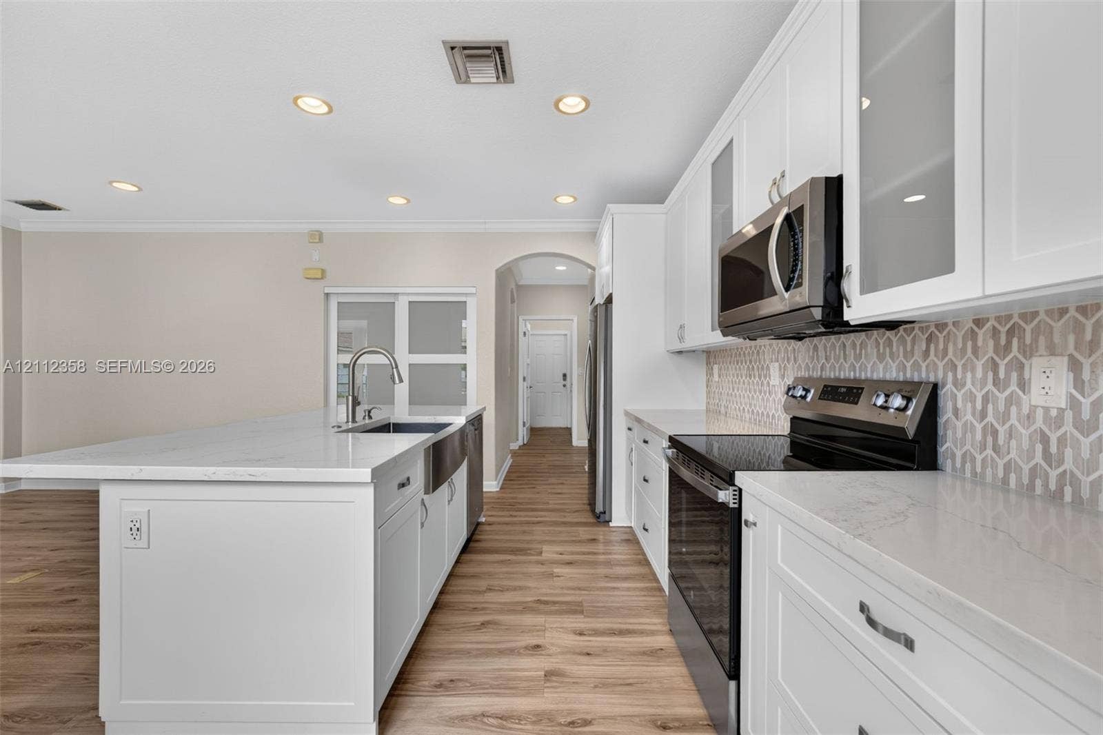 1611 SE 16th Street, Homestead, FL 33035 Kitchen featuring white cabinetry, stone-look countertops, stainless steel appliances, a farmhouse-style sink, and patterned tile backsplash