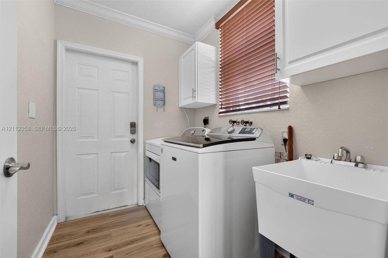 1611 SE 16th Street, Homestead, FL 33035 Laundry room featuring wood-finish flooring, white cabinetry, a utility sink, and window blinds