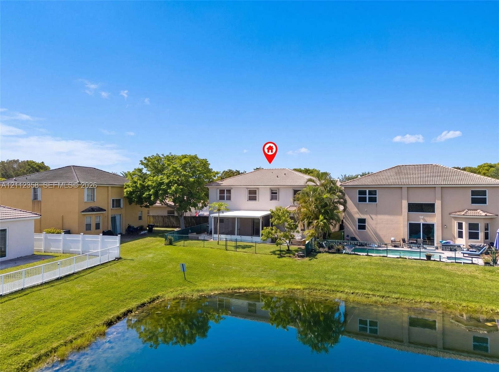 1611 SE 16th Street, Homestead, FL 33035 Two-story residence featuring a screened-in lanai, tile roof, and waterfront positioning overlooking a retention pond