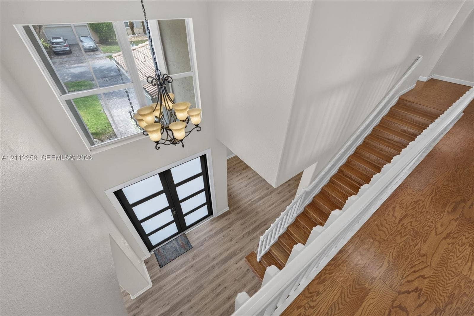 1611 SE 16th Street, Homestead, FL 33035 Double-height entryway featuring wood-finish flooring, a multi-pane glass door, a metal chandelier, and a staircase with white balusters
